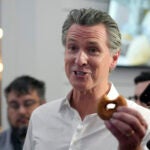 California Gov. Gavin Newsom holds a donut while greeting people.