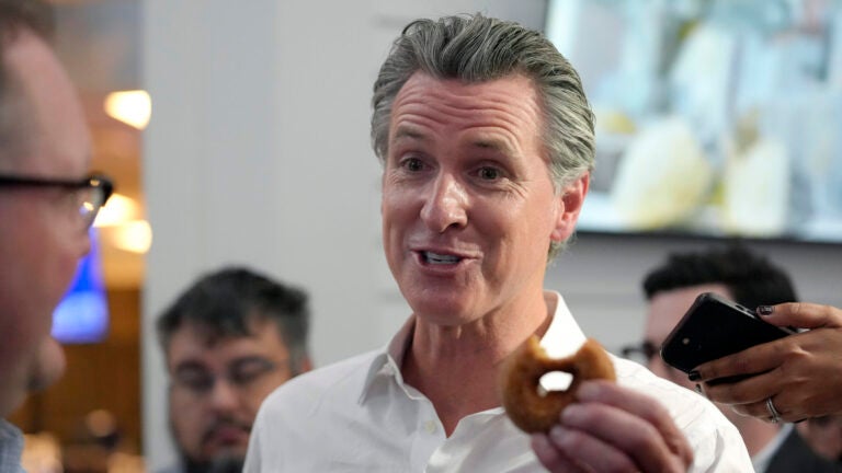 California Gov. Gavin Newsom holds a donut while greeting people.