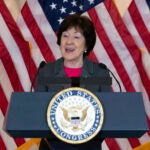 Sen. Susan Collins, R-Maine, speaks in front of American flags.