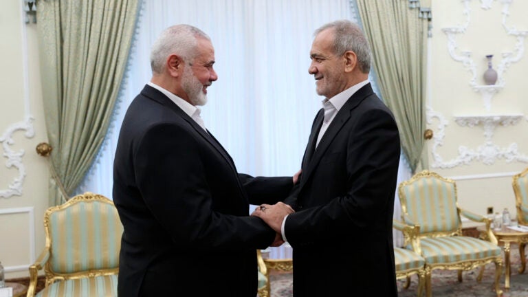 President Masoud Pezeshkian, right, shakes hands with Hamas chief Ismail Haniyeh.