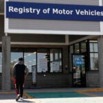 A man walks to the Commonwealth of Massachusetts Registry of Motor Vehicles office in Lawrence, Mass.