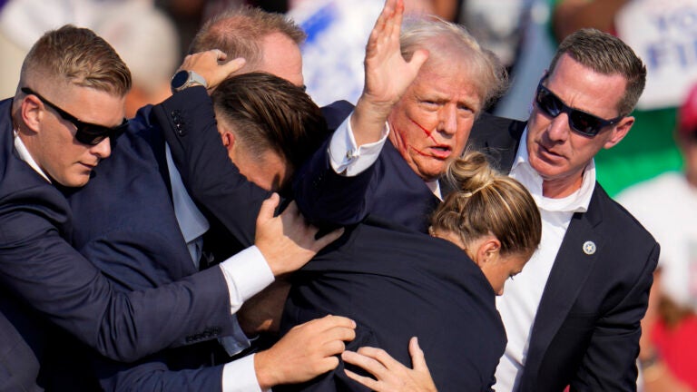 Republican presidential candidate former President Donald Trump is helped off the stage by U.S. Secret Service agents at a campaign event in Butler, Pa., on Saturday, July 13, 2024.