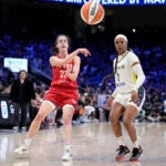 Indiana Fever's Caitlin Clark (22) makes a pass as Dallas Wings' Odyssey Sims (2) defends in the first half of a WNBA basketball game.