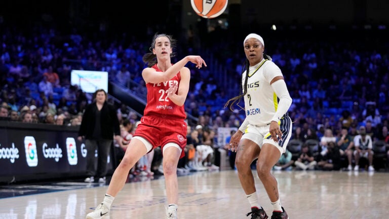 Indiana Fever's Caitlin Clark (22) makes a pass as Dallas Wings' Odyssey Sims (2) defends in the first half of a WNBA basketball game.