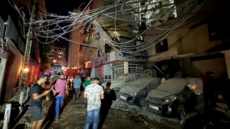 People gather near a destroyed building that was hit by an Israeli airstrike in the southern suburbs of Beirut, Lebanon, Tuesday, July 30, 2024.