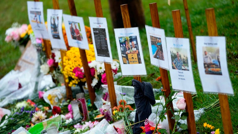 FILE - Rain soaked memorials for those who died in a mass shooting sit along the roadside by Schemengees Bar & Grille, Oct. 30, 2023, in Lewiston, Maine.