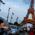 Passengers in the back of a taxi film themselves as they leave the Eiffel Tower decorated with the Olympic rings ahead of the 2024 Summer Olympics in Paris.