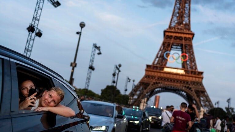 Passengers in the back of a taxi film themselves as they leave the Eiffel Tower decorated with the Olympic rings ahead of the 2024 Summer Olympics in Paris.