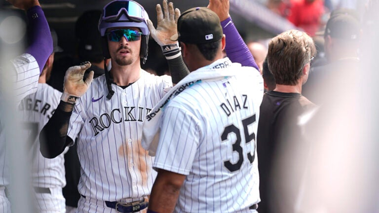 Colorado Rockies' Brenton Doyle, center, is congratulated as he returns to the dugout after hitting a grand slam off Red Sox relief pitcher Chase Anderson in the sixth inning.