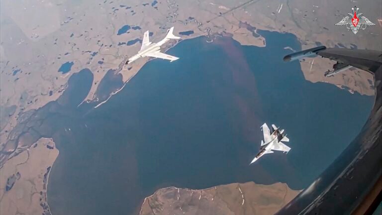 In this photo taken from video released by Russian Defense Ministry Press Service on Thursday, July 25, 2024, A H-6K long-range bomber of the Chinese air force, upper left, is seen escorted by a Su-30 fighter of the Russian air force during a joint Russia-China air patrol.