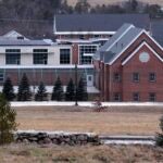 FILE - The Sununu Youth Services Center is seen amongst the trees on Jan. 28, 2020, in Manchester, N.H. Gordon Thomas Searles, a former worker charged with sexually assaulting a teenage boy at the facility in the 1990s, died Sunday while awaiting trial, according to his attorney.