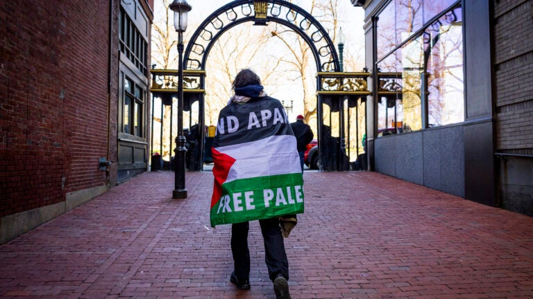 A man wears a Palestinian flag as he walks through an area where a pro-Palestinian encampment had been set up before it was dismantled by police at Emerson College in Boston, on Thursday, April 25, 2024.