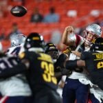 LANDOVER, MD - AUGUST 25: Drake Maye #10 of the New England Patriots is hit as he passes against the Washington Commanders in the first quarter of a preseason game at Commanders Field on August 25, 2024 in Landover, Maryland.