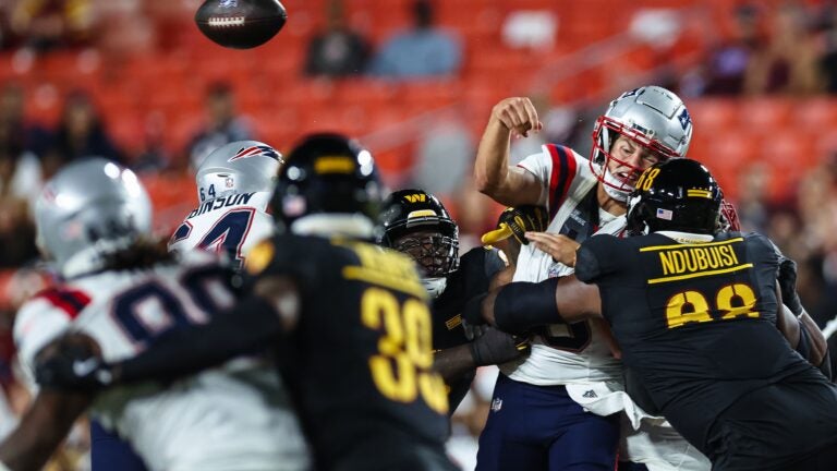 LANDOVER, MD - AUGUST 25: Drake Maye #10 of the New England Patriots is hit as he passes against the Washington Commanders in the first quarter of a preseason game at Commanders Field on August 25, 2024 in Landover, Maryland.