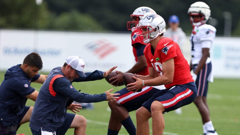 Quarterbacks Drake Maye (R) and Jacoby Brissett look to pass during Patriots practice at Gillette Stadium.