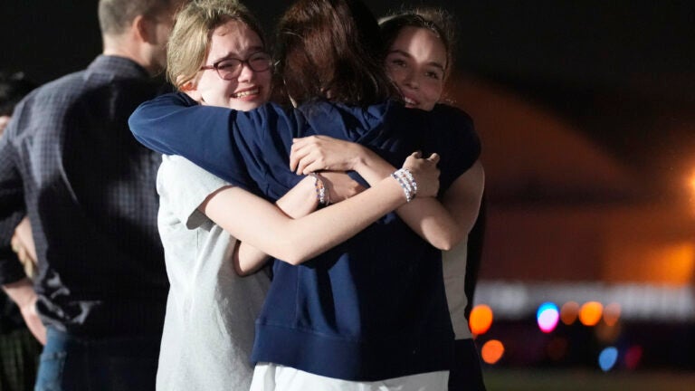 Alsu Kurmasheva, center, hugs her daughters Miriam Butorin, left, and Bibi Butorin at Andrews Air Force Base, Md.