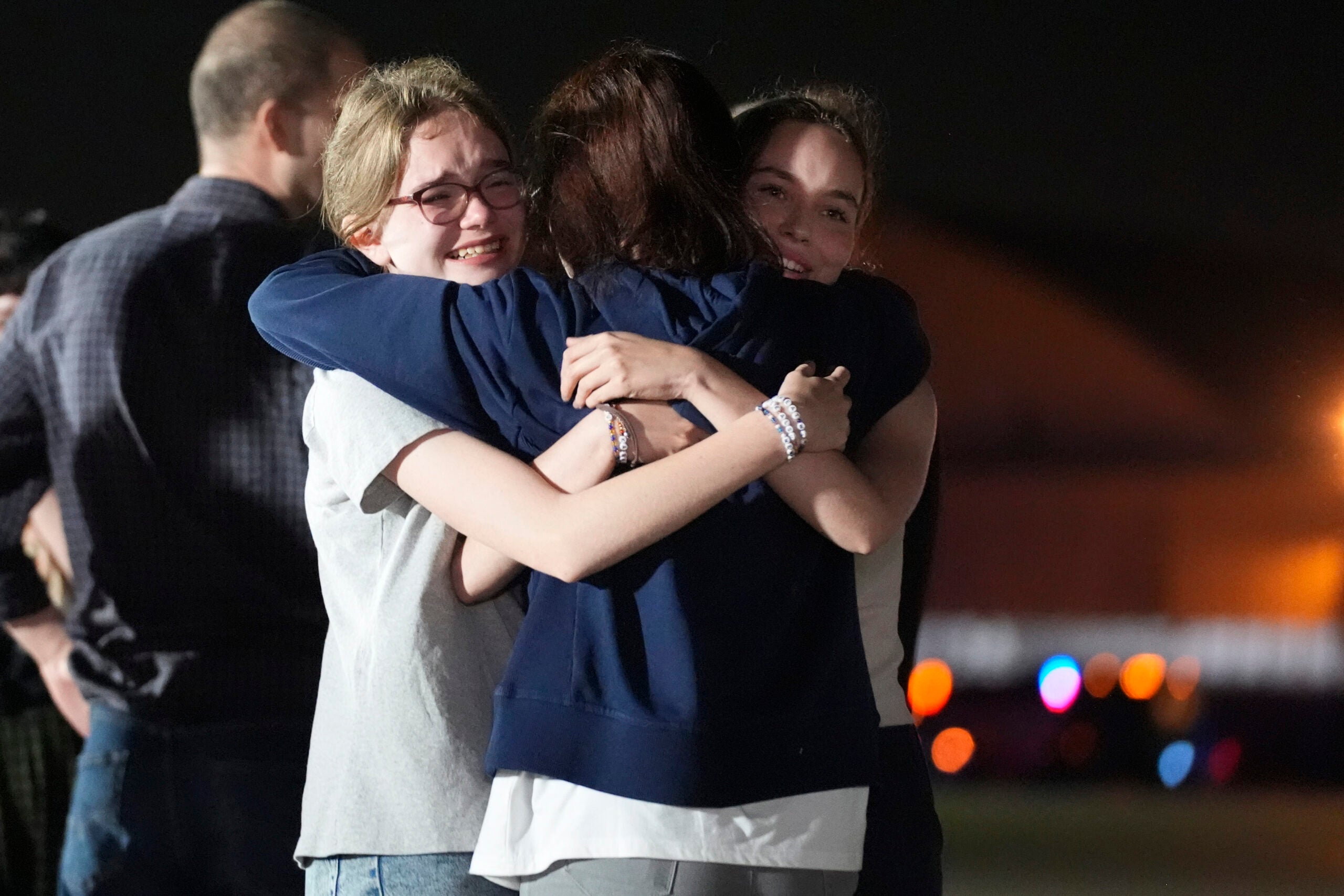 Alsu Kurmasheva, center, hugs her daughters Miriam Butorin, left, and Bibi Butorin at Andrews Air Force Base, Md.