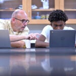 History teacher Matt Brophy, left, works with Flerentin “Flex” Jean-Baptiste, 16, of Medford, Mass.