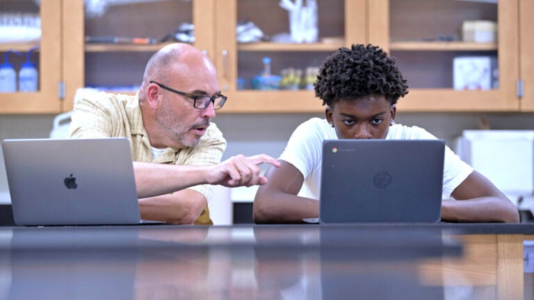 History teacher Matt Brophy, left, works with Flerentin “Flex” Jean-Baptiste, 16, of Medford, Mass.