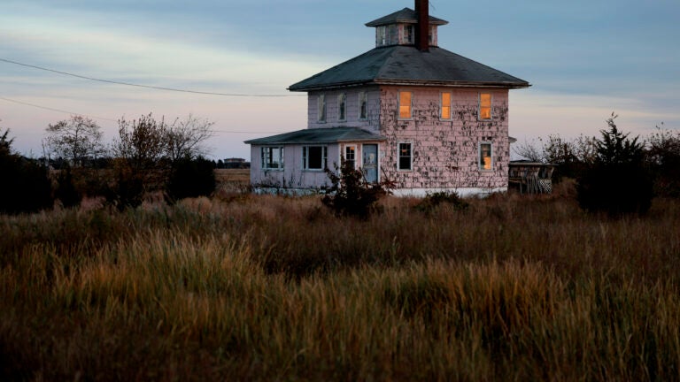 The setting sun is reflected in the windows of the iconic Pink House on the causeway to Plum Island. The building is owned by US Fish and Wildlife, and they've announced they are tearing it down.