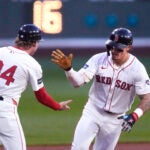 Jarren Duran of the Red Sox is congratulated by third base coach Kyle Hudson while rounding the bases on his solo home run during the first inning.