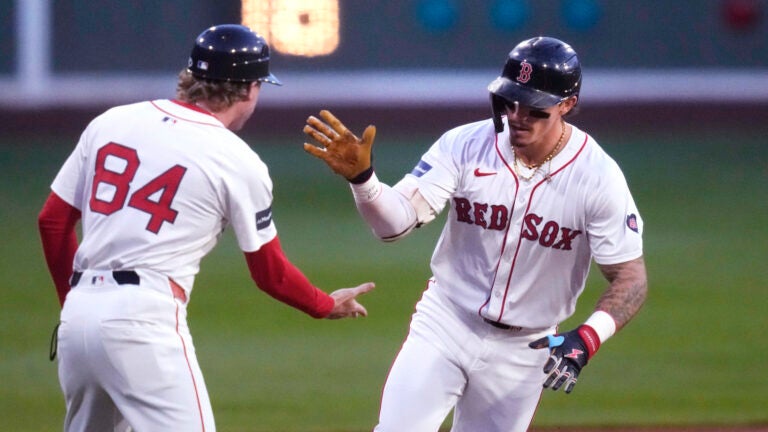 Jarren Duran of the Red Sox is congratulated by third base coach Kyle Hudson while rounding the bases on his solo home run during the first inning.