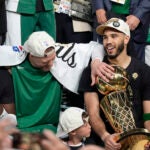 Boston Celtics forward Jayson Tatum, center, holds the Larry O'Brien Championship Trophy as he celebrates with center Kristaps Porzingis, left, and guard Jaylen Brown, right, after the Celtics won the NBA championship with a Game 5 victory over the Dallas Mavericks on Monday, June 17, 2024, in Boston.