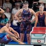 Katie Ledecky, of United States, sits on the pool deck with teammates during the women's 4x200-meter freestyle relay final at the 2024 Summer Olympics.