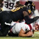 Drake Maye is tackled after recovering his own fumble by Commanders defensive end Andre Jones Jr. during a preseason game.