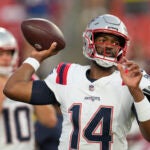 New England Patriots quarterbacks Jacoby Brissett (14) and Drake Maye (10) warm up before a preseason NFL football game against the Washington Commanders, Sunday, Aug. 25, 2024, in Landover, Md.