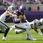Minnesota Vikings quarterback J.J. McCarthy (9) is hit by Las Vegas Raiders safety Jaydon Grant (40) as he scramble for yards during the first half of an NFL football game.