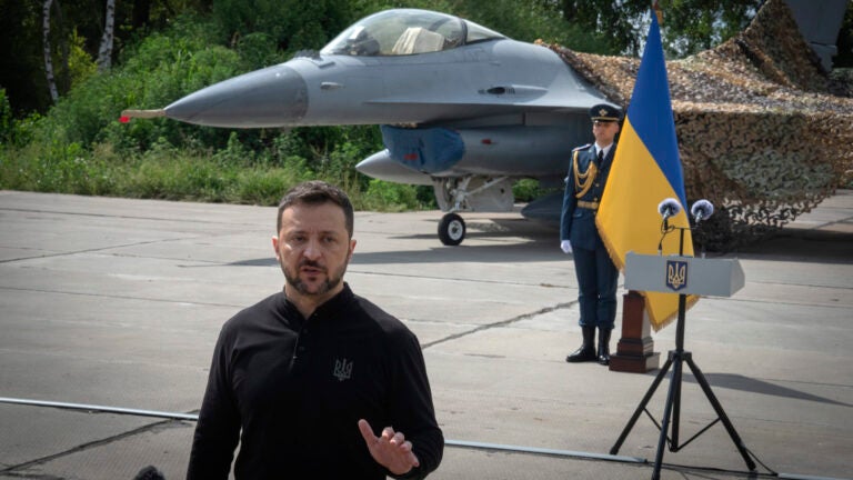 Ukraine's President Volodymyr Zelenskyy answers media questions standing against the background of Ukraine's Air Force's F-16 fighter jets in an undisclosed location in Ukraine, Sunday, Aug. 4, 2024.