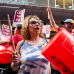 Toula Savvidis cheers and hits a Home Depot bucket during a rally led by the Boston’s Local 26 organization supporting hotel workers in front of the Hyatt Regency in downtown Boston.