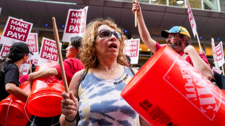 Toula Savvidis cheers and hits a Home Depot bucket during a rally led by the Boston’s Local 26 organization supporting hotel workers in front of the Hyatt Regency in downtown Boston.