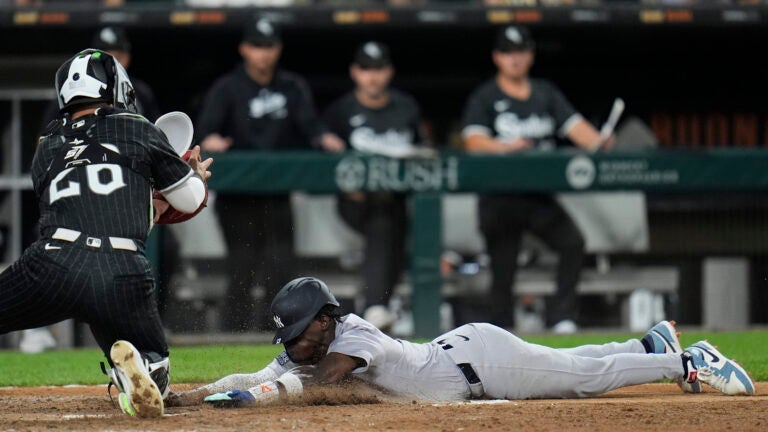 New York Yankees' Jazz Chisholm Jr., right, dives by Chicago White Sox catcher Korey Lee, left, to score on a single by Anthony Volpe during the fifth inning of a baseball game in Chicago.