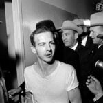 Lee Harvey Oswald talks to the media as he is led down a corridor of the Dallas police station in 1963.