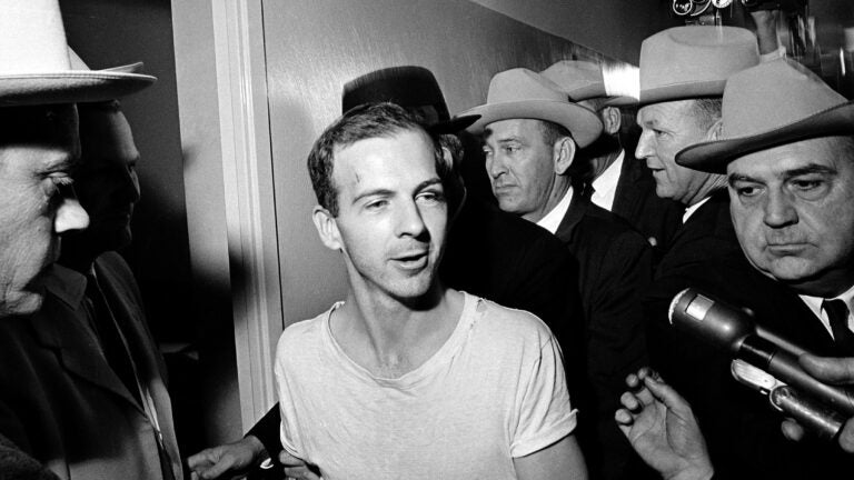 Lee Harvey Oswald talks to the media as he is led down a corridor of the Dallas police station in 1963.