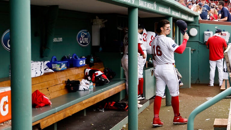 Jarren Duran grabs his hat as he stands in a near empty Red Sox dugout.
