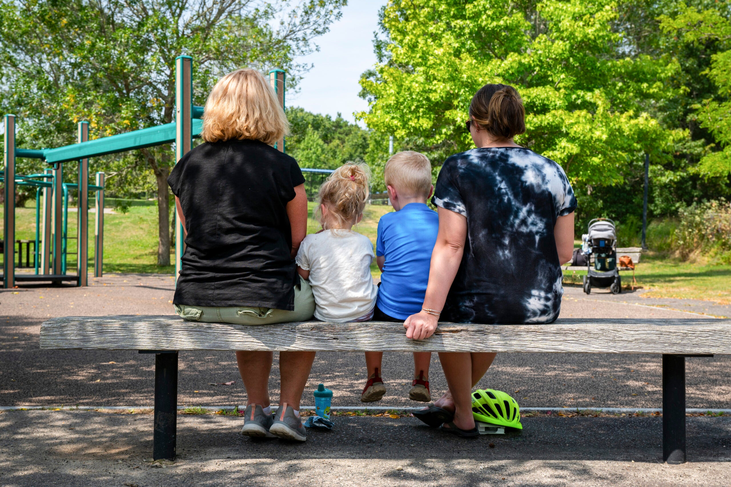 Sue Ryan, seus netos e filha sentados no playground Forges Field em Plymouth, Massachusetts.