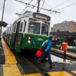 A person crosses in front of a Green Line B train.