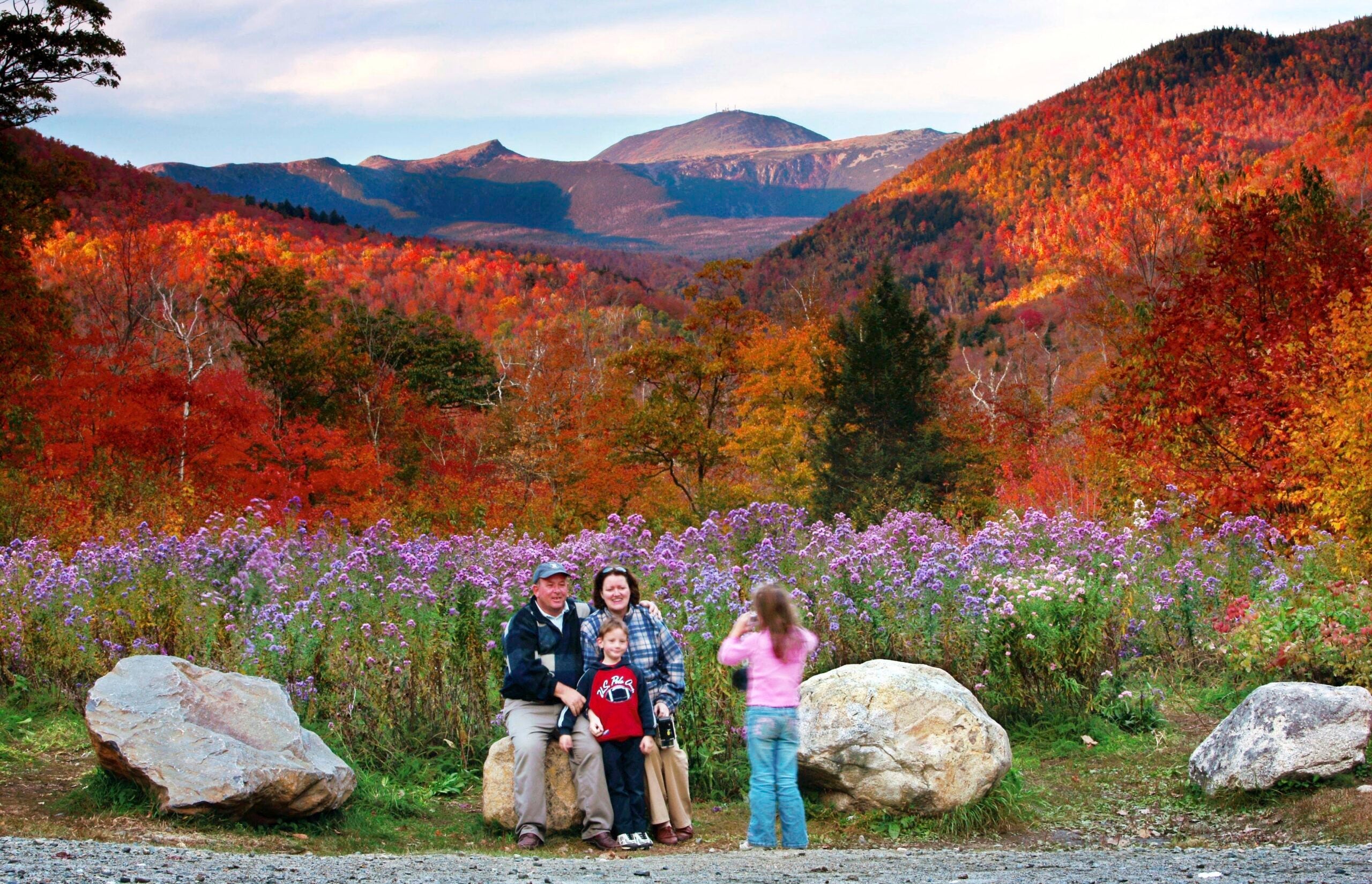 Wildflowers, fall foliage, and Mt. Washington serve as a backdrop for a family at Crawford Notch State Park in New Hampshire.