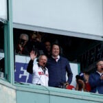 Longtime radio announcer Joe Castiglione, left, waves to the crowd as he’s honored during the final game of the season at Fenway Park.