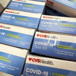 At-Home COVID-19 Test kits are displayed at a drug store.
