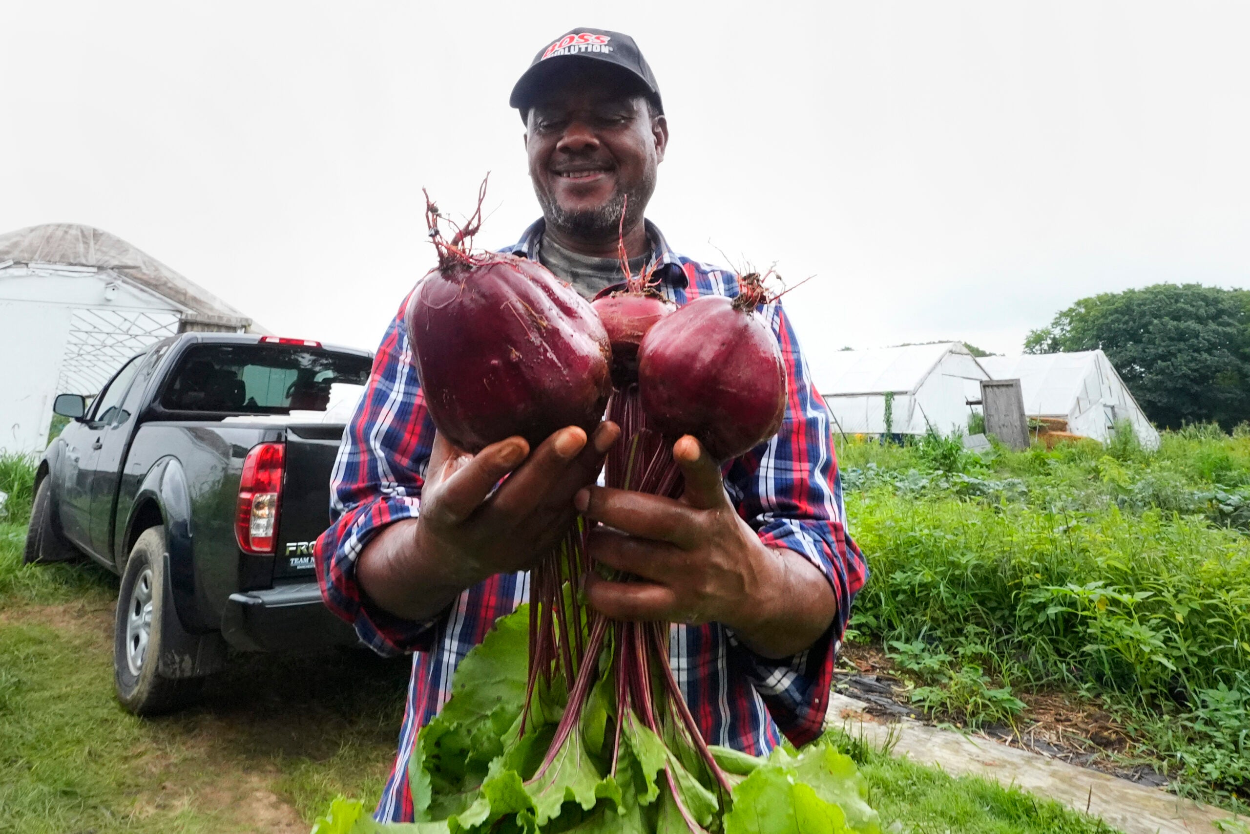 Farmer Sylvain Bukasa, a refugee from Democratic Republic of the Congo, smiles while showing the beets grown on his plot at Fresh Start Farm.