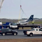 Officials remove a small plane that landed at Logan International Airport.