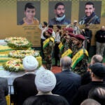 Hezbollah fighters salute as they stand next to the coffins of four victims.