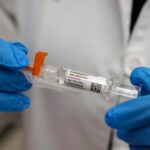 A pharmacist holds a COVID-19 vaccine at a pharmacy.