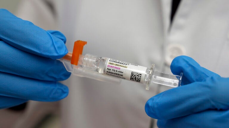 A pharmacist holds a COVID-19 vaccine at a pharmacy.
