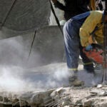 An emergency worker cuts concrete blocks.
