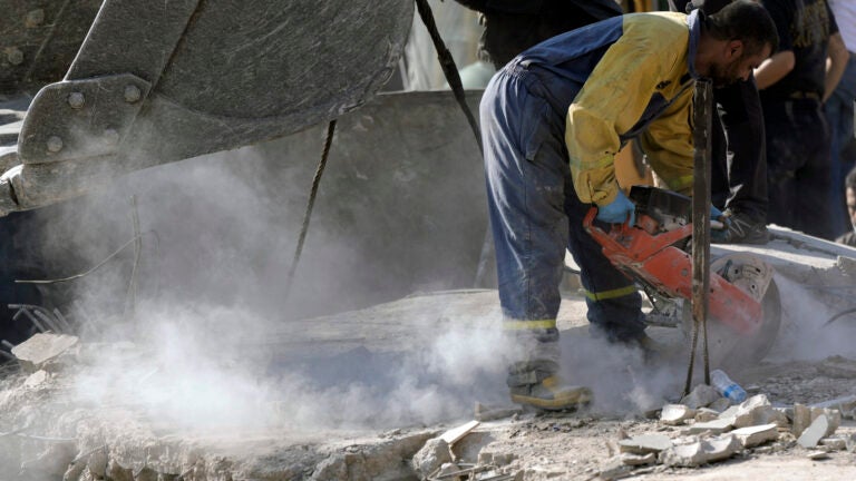 An emergency worker cuts concrete blocks.